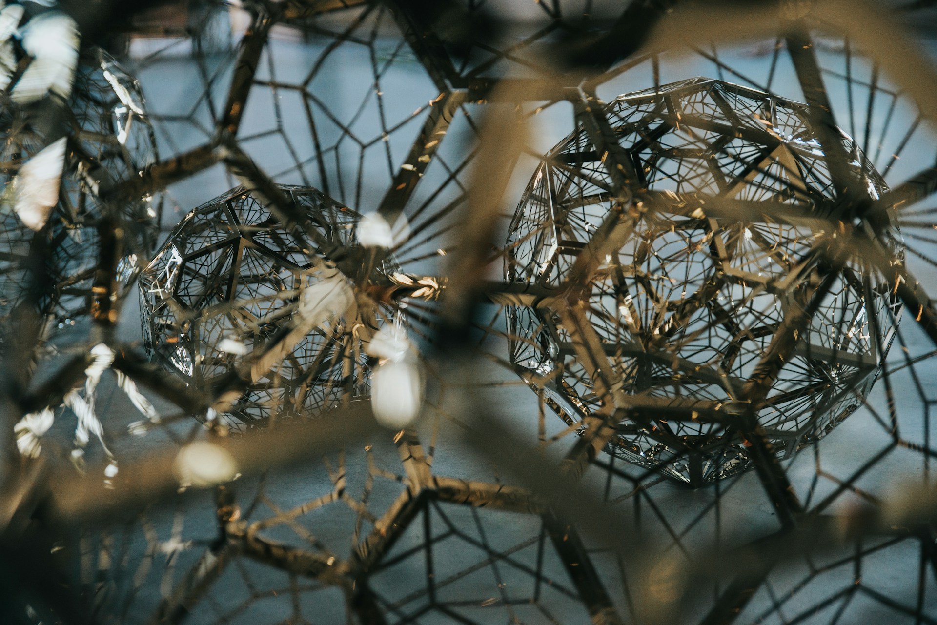 Abstrakte, geometrische Strukturen aus filigranen Metallverstrebungen, die an digitale Modellarchitekturen erinnern und visuell die Funktionsweise von isg twinstore als Basis für digitale Zwillinge symbolisieren.