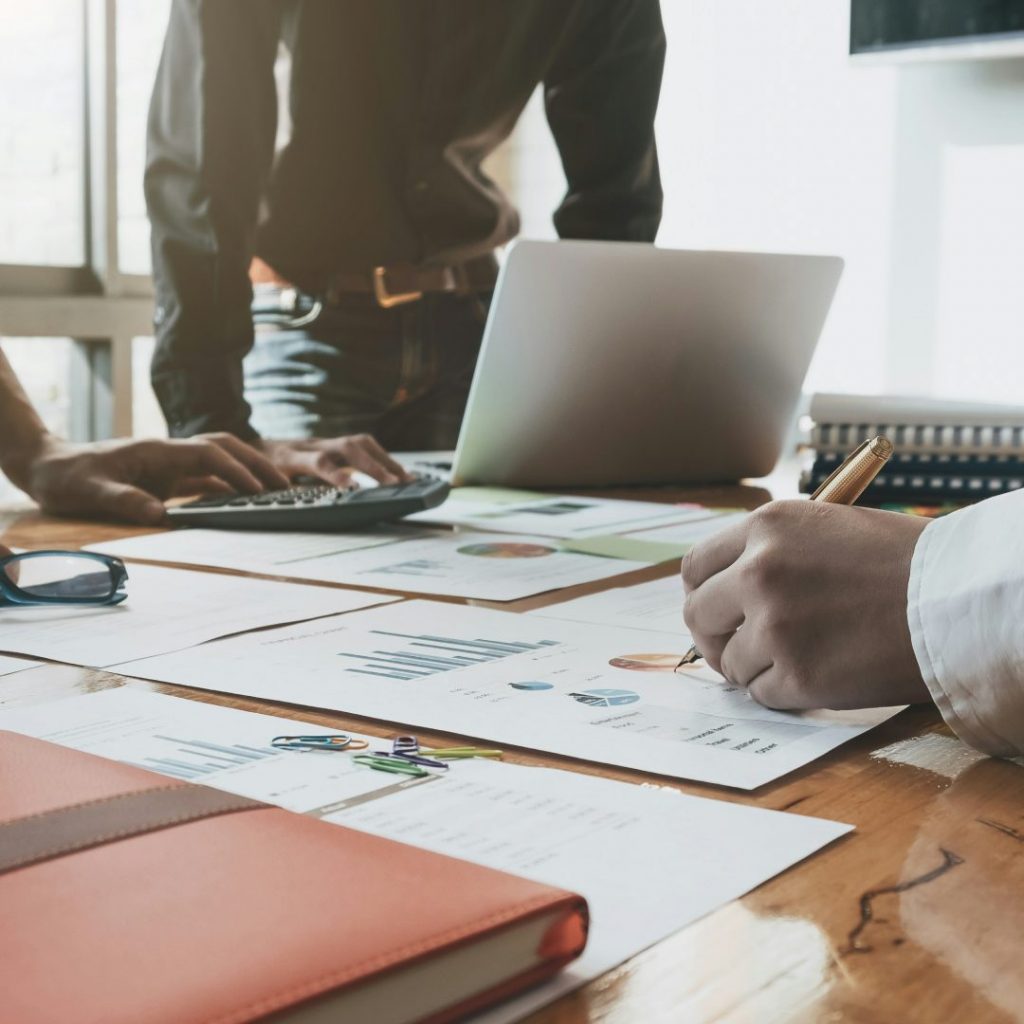 Geschäftspersonen analysieren Finanzdiagramme und arbeiten gemeinsam am Laptop – symbolisch für die Forschungszulage als strategischen Wachstumsbooster für Unternehmen.