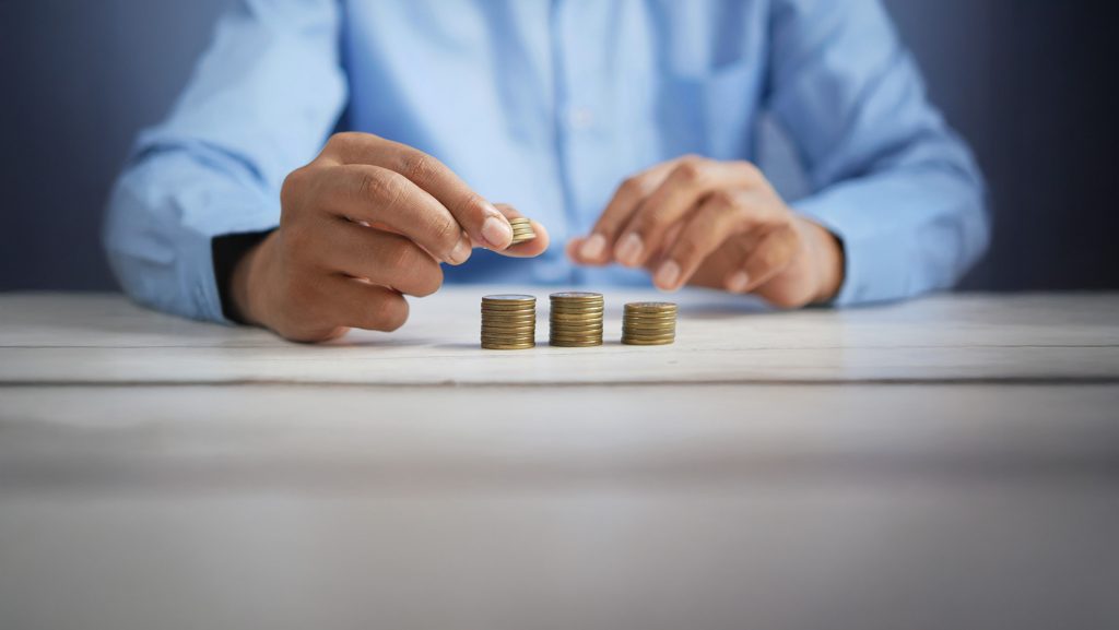 Eine Person ordnet und stapelt Münzen auf einem Tisch – eine symbolische Darstellung für die finanzielle Planung und Strukturierung des Bundeshaushalts 2025.