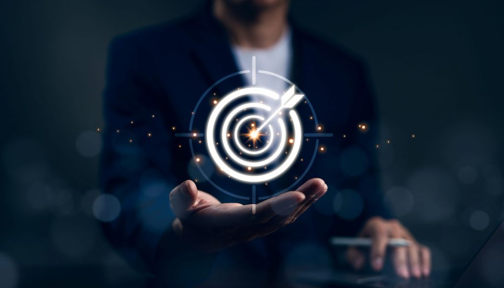 Person in Business-Outfit hält eine digitale Zielscheibe mit Pfeil in der Mitte, symbolisch für präzise Zielerreichung und Innovation im Rahmen der Hightech Agenda Deutschland.