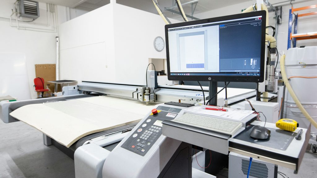 Digital gesteuerte Schneidemaschine mit Benutzeroberfläche und Monitor – stellvertretend für moderne industrielle Steuerungstechnik und digitale Zwillinge im Maschinenbau, wie sie im Projekt TwinStore von ISG Industrielle Steuerungstechnik entwickelt wurden.