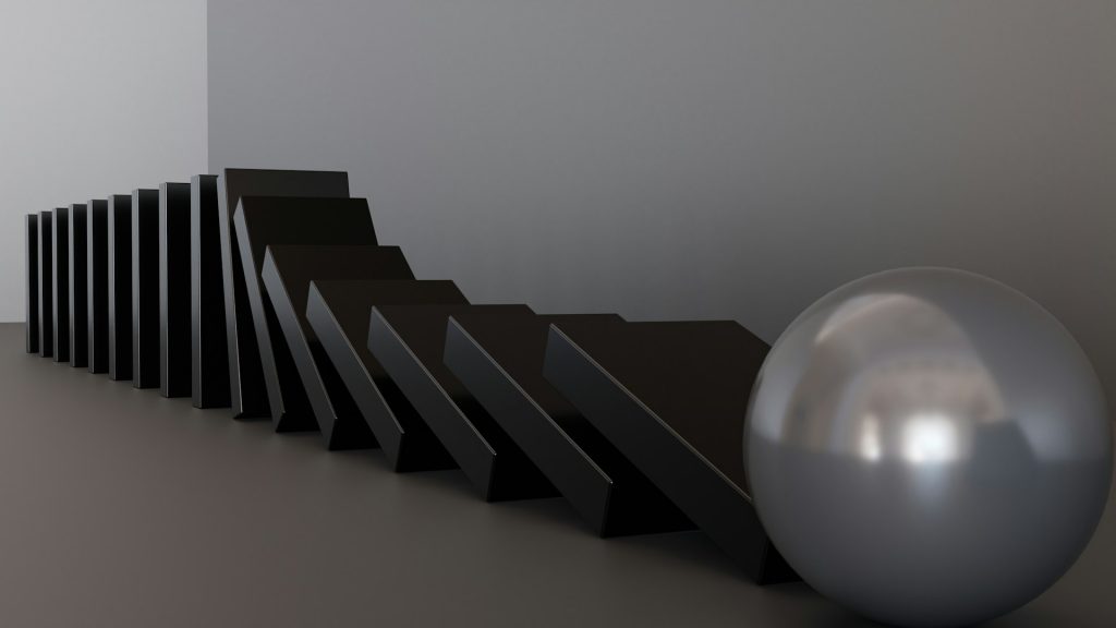 Eine Reihe schwarzer Dominosteine kippt nacheinander um und wird von einer glänzenden silbernen Kugel gestoppt. Das Bild symbolisiert den Dominoeffekt von Entscheidungen und die Bedeutung strategischer Planung für die Forschungszulage 2026.