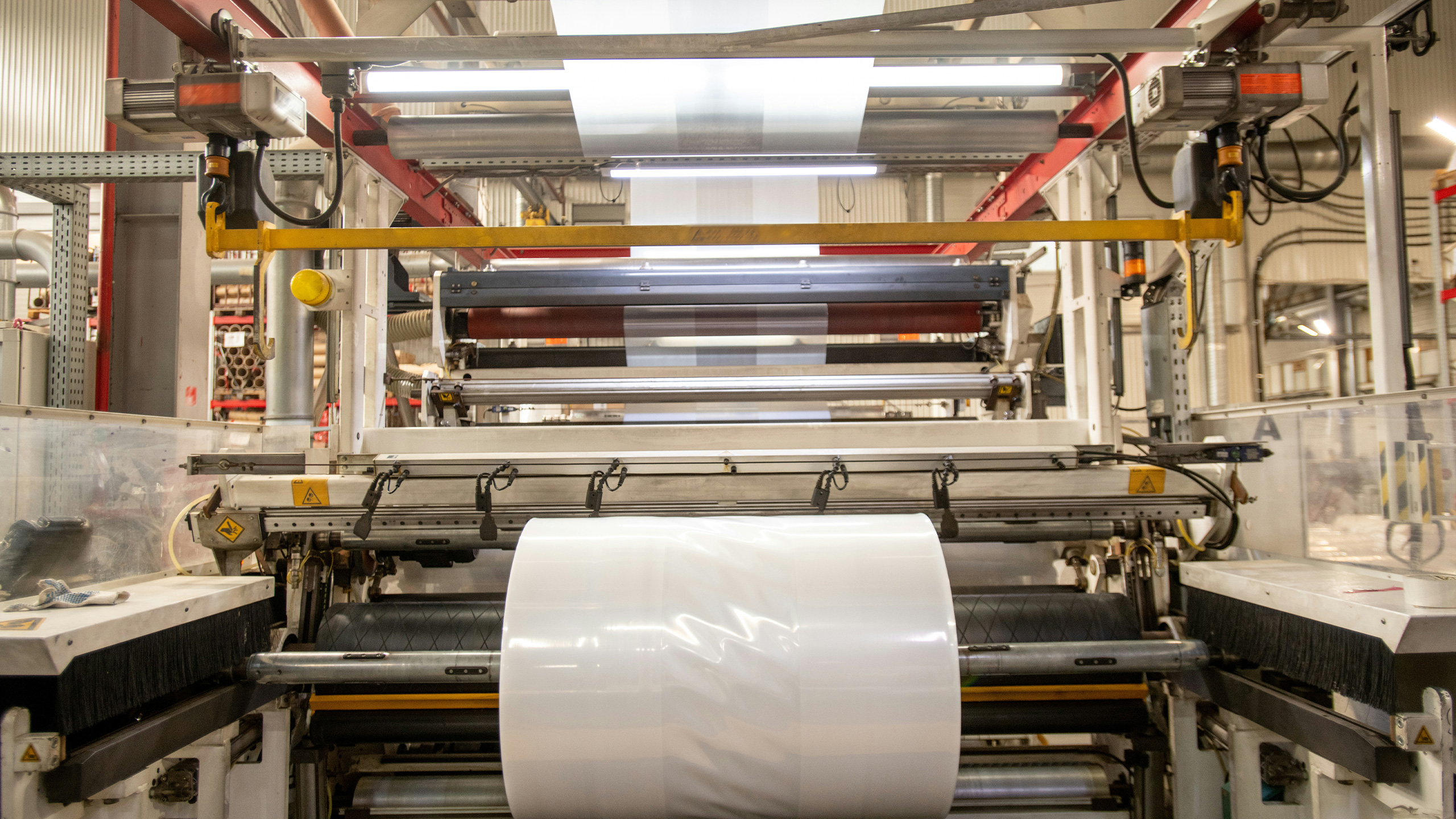 Industrielle Extrusionsanlage mit laufender Folienproduktion, bei der Mess- und Prüftechnik von Göttfert zur Qualitätsüberwachung eingesetzt werden kann.