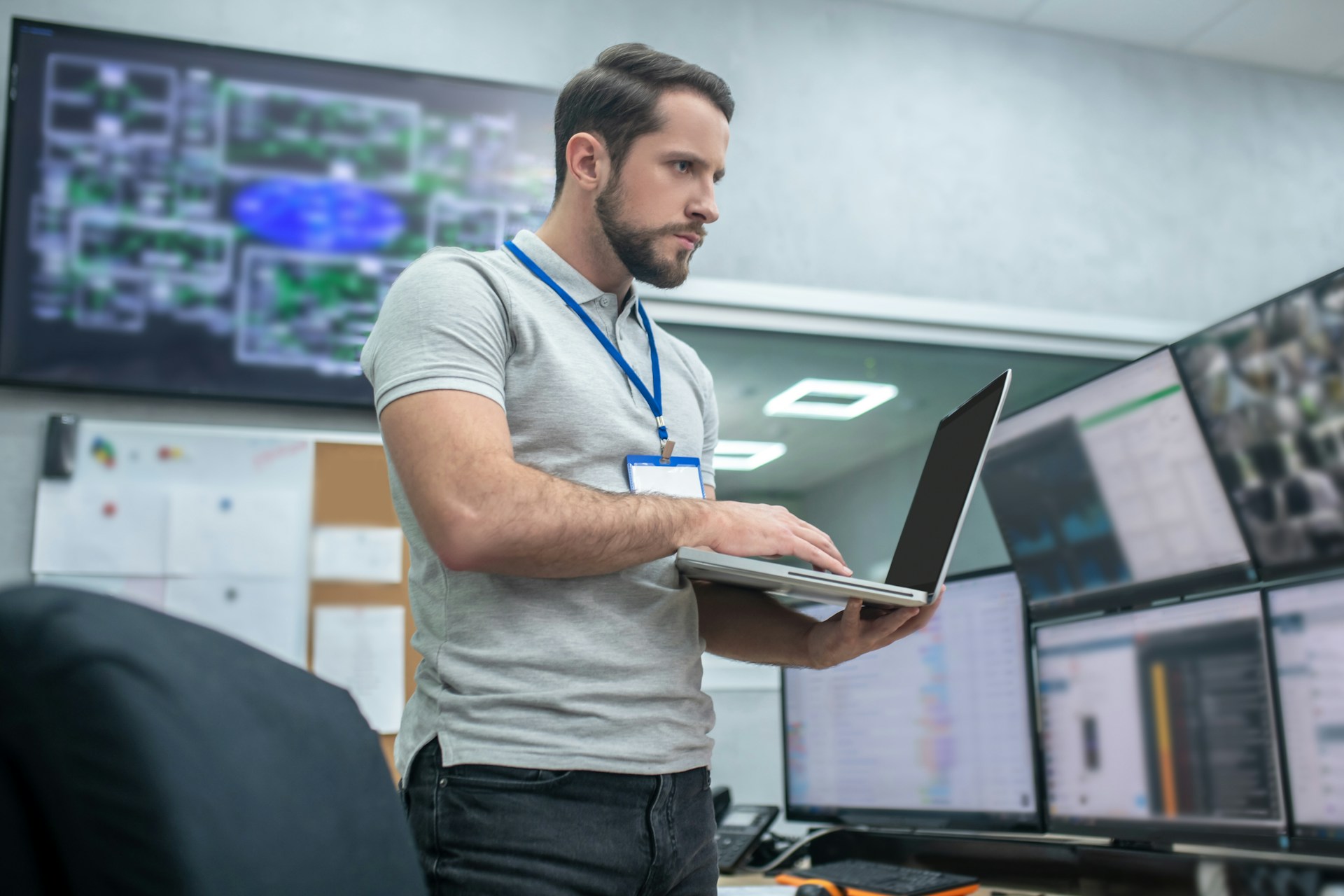 Eine Person arbeitet in einer Leitwarte mit mehreren Monitoren und einem Laptop, auf denen Prozessdaten und Anlagenvisualisierungen angezeigt werden, während ISG-dirigent für die zentrale Ablauf- und Steuerungslogik genutzt wird.