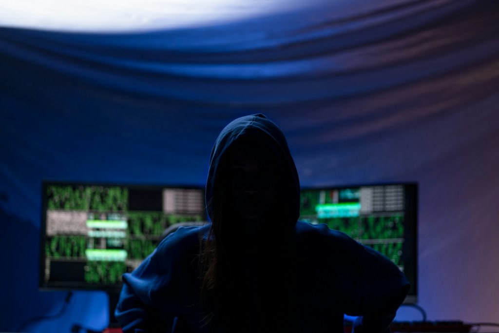 Symbolische Darstellung digitaler Verteidigungsprojekte: Silhouette einer Person vor mehreren Monitoren mit technischen Daten und Code.