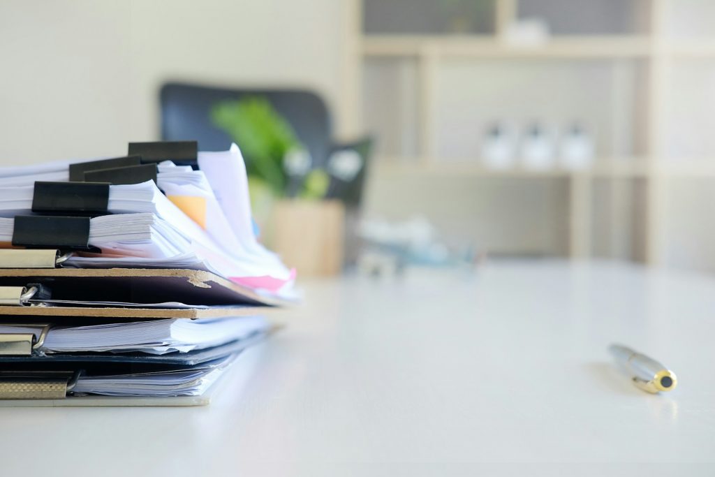 Fördermittel für innovative Unternehmen erleichtern die Umsetzung von Innovationsvorhaben. Das Bild zeigt einen Stapel von Aktenordnern und Dokumenten als Symbol für Antragsprozesse, Fördermanagement und bürokratische Anforderungen.