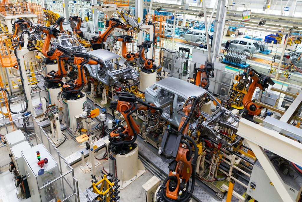 Automatisierte Fahrzeugproduktion mit Industrierobotern zeigt den Einsatz von KI in Wertschöpfungsketten zur intelligenten Steuerung, Qualitätskontrolle und Effizienzsteigerung in der Fertigung.