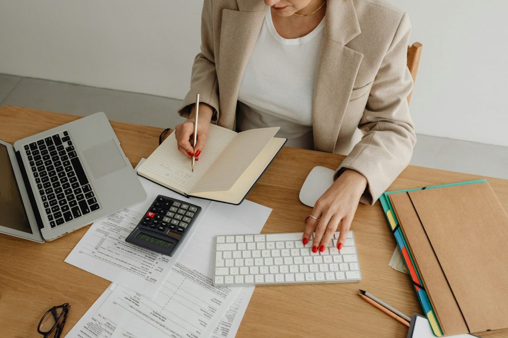 Person analysiert Daten und Geschäftsunterlagen am Arbeitsplatz. Das Bild veranschaulicht, wie KI in Wertschöpfungsketten datenbasierte Entscheidungen, Prozessoptimierung und effiziente Ressourcenplanung unterstützt.